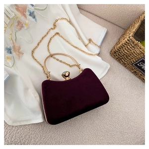 Elegant deep purple velvet evening handbag with gold handle and diamond clasp on sofa