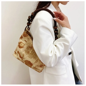Detailansicht der Retro-Seidenhandtasche mit Blumenprint und Holzperlen-Schulterriemen
