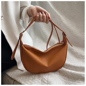 Close-up of caramel pebble grain leather crescent bag with elegant gold hardware accents