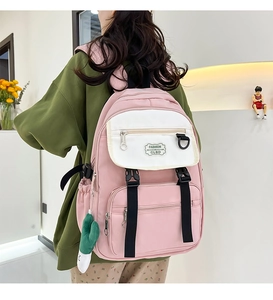 Détail d'un sac à dos en nylon rose et beige avec boucles noires et pendentif cactus