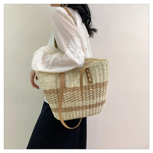 Detail of woven straw tote bag with brown leather straps and striped pattern texture