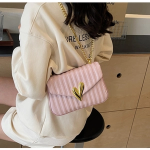 Detail of pink quilted PU leather bag with gold heart clasp and metal chain strap