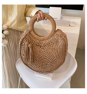 Detail of round straw handbag with double tassels and woven texture for summer resort style