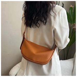 Detail of trendy caramel crescent bag with pebble leather texture worn by a model