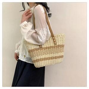 Detail of woven tote bag featuring bicolor stripes and durable brown leather handles