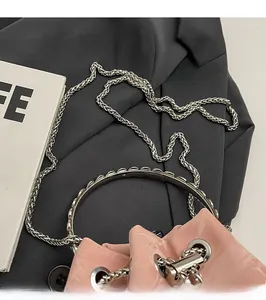 Detail of pink velvet bucket bag with silver metal ring handle and sleek chain strap