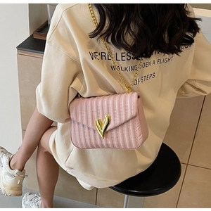 Detail of pink quilted PU leather crossbody bag featuring a golden heart-shaped metal clasp