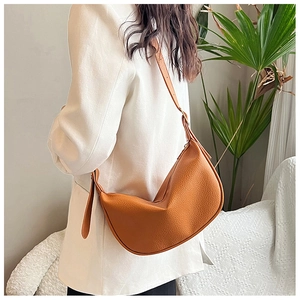 Detailed view of brown lychee leather crescent bag worn by a model in a modern interior