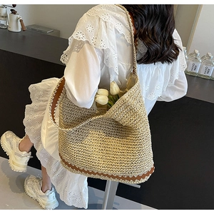 Detail showing woven texture of a straw tote bag with wavy leather trim and lace lining