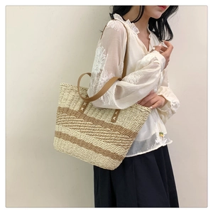 Fashionable woven straw tote bag with brown leather handles worn by a model in white lace