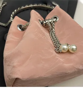 Detailed close-up of pink drawstring bucket bag with silver metal eyelets and pearl beads