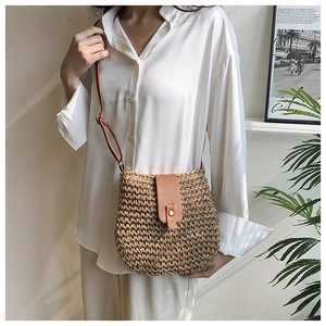Detailed close-up of handmade woven straw crossbody bag with brown leather strap