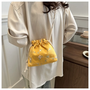 Detailed close-up of yellow floral embroidery and drawstring on cotton linen crossbody bag