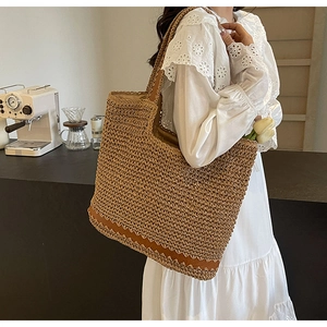 Detail showing the woven texture and dark brown scalloped trim of the raffia tote bag