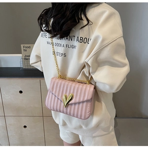 Detail of pink quilted PU leather bag with heart-shaped gold clasp and chain strap