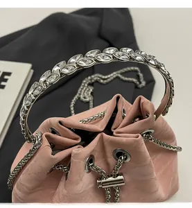 Detail of pink velvet bucket bag featuring silver leaf-shaped crystal handle and metal chain
