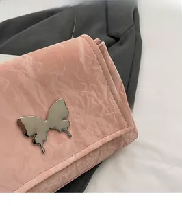 Détail du sac cabas en similicuir plissé rose avec ornement papillon argenté