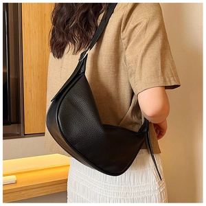 Close-up of black lychee grain leather crossbody bag with golden metal hardware detail