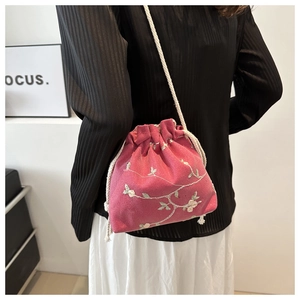 Detailed view of pink embroidered drawstring crossbody bag with floral pattern
