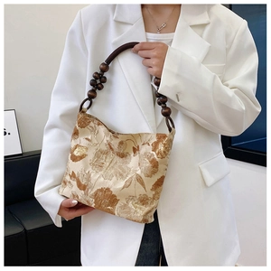 Detail der goldene Jacquard-Blumenmuster und runder Holzperlen-Griff an der Handtasche