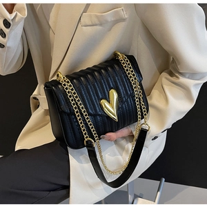 Detail of black quilted PU leather crossbody bag featuring a golden heart-shaped metal lock