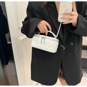 Detailed view of white quilted PU crossbody bag with chain strap on a black blazer