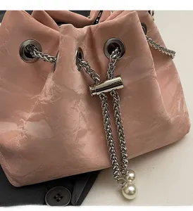 Close-up of pink bucket bag with glossy crinkled texture, silver hardware and pearl charms