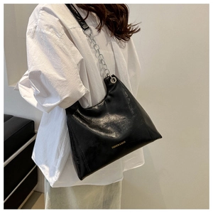 Détail du sac à bandoulière en PU noir avec chaîne argentée et logo doré chic