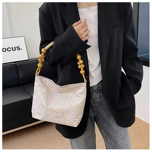 Detail der rosa Seidenhandtasche mit kunstvollem Holzperlengriff an einem Modell