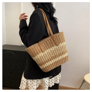 Detailed view of woven straw tote bag with brown leather straps and stripe pattern