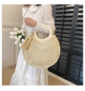 Detail of straw handbag with large round handles and decorative tassel for summer