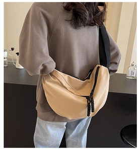 Chic beige half-moon nylon crossbody bag with wide black strap shown on model back
