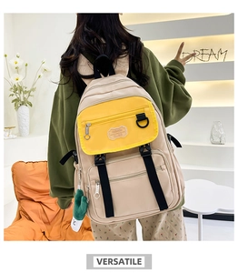 Détail d'un sac à dos en nylon beige et jaune avec un pendentif mignon en peluche verte