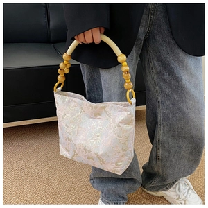 Detailaufnahme einer floralen Jacquard-Seidenhandtasche mit Akzenten am Holzperlengriff