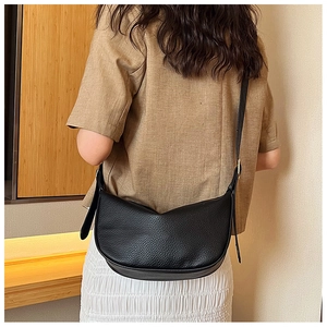 Detail view of black lychee grain crescent bag with adjustable gold buckle on a model