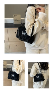Gros plan sur un sac cabas noir matelassé avec charm papillon argenté et bandoulière