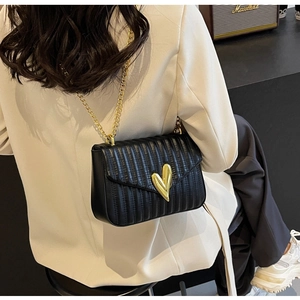 Detail of black quilted PU cross-body bag featuring a gold heart V-clasp and chain strap
