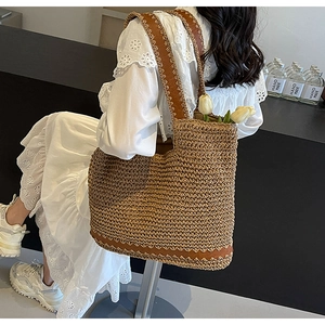 Close-up of woven straw tote bag with brown leather trim and white tulip decorations