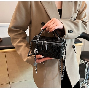 Close-up of black quilted PU leather crossbody bag with silver chain and ball charm detail