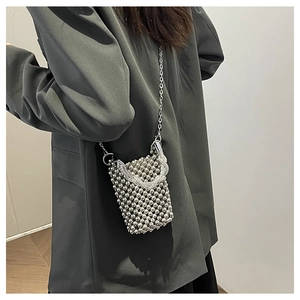 Gros plan d'un mini sac à bandoulière en perles argentées porté par un mannequin