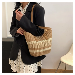Detail of woven straw handbag featuring brown and cream stripes and leather strap
