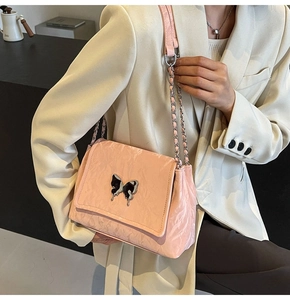 Détail du sac à bandoulière en cuir verni rose avec un fermoir papillon en métal