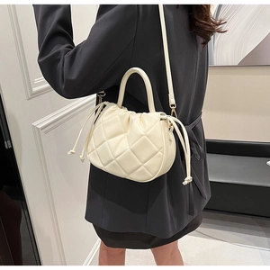 Detail of a beige quilted crossbody bag with diamond stitching and drawstring closure