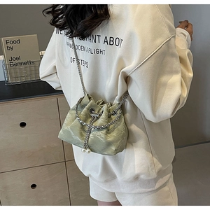 Detail view of the drawstring bucket bag featuring light green velvet and pearl charms
