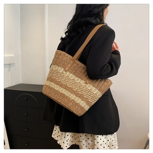 Detailed side view of large woven straw tote with brown leather straps and striped pattern