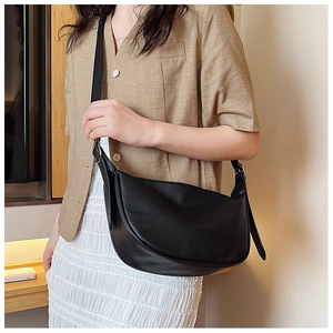 Close-up of black lychee grain crescent crossbody bag showing texture and adjustable strap