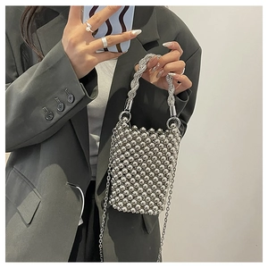 Détail d'un mini sac perlé argenté avec poignée en spirale et fine chaîne en métal