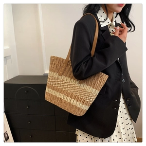Detail view of woven straw tote bag with brown leather straps on a professional model