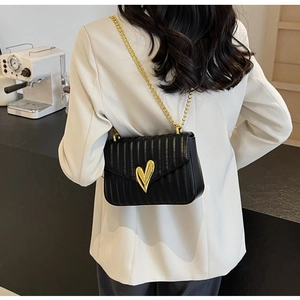 Detail of a black PU leather chain bag with a gold heart-shaped metal buckle and quilting