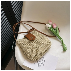 Chic beige woven crossbody bag with brown leather flap and vintage metal buckle on a chair